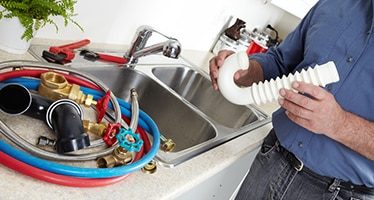 Plumber Has Parts Laid Out For Fixing Sink — Plumbers & Electricians in Shellharbour, NSW